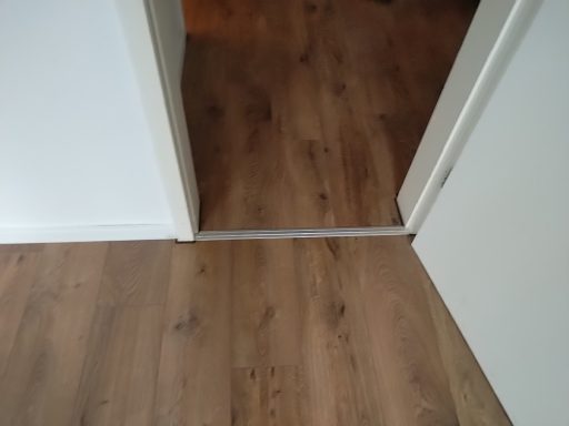Laminatboden mit weißen Sockelleisten und Übergangsleiste